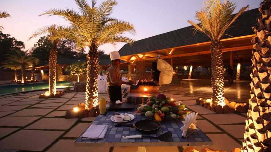Crackling bonfire under starry sky surrounded by guests on garden benches