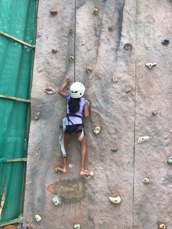 Guest scaling textured outdoor climbing wall with safety belay ropes